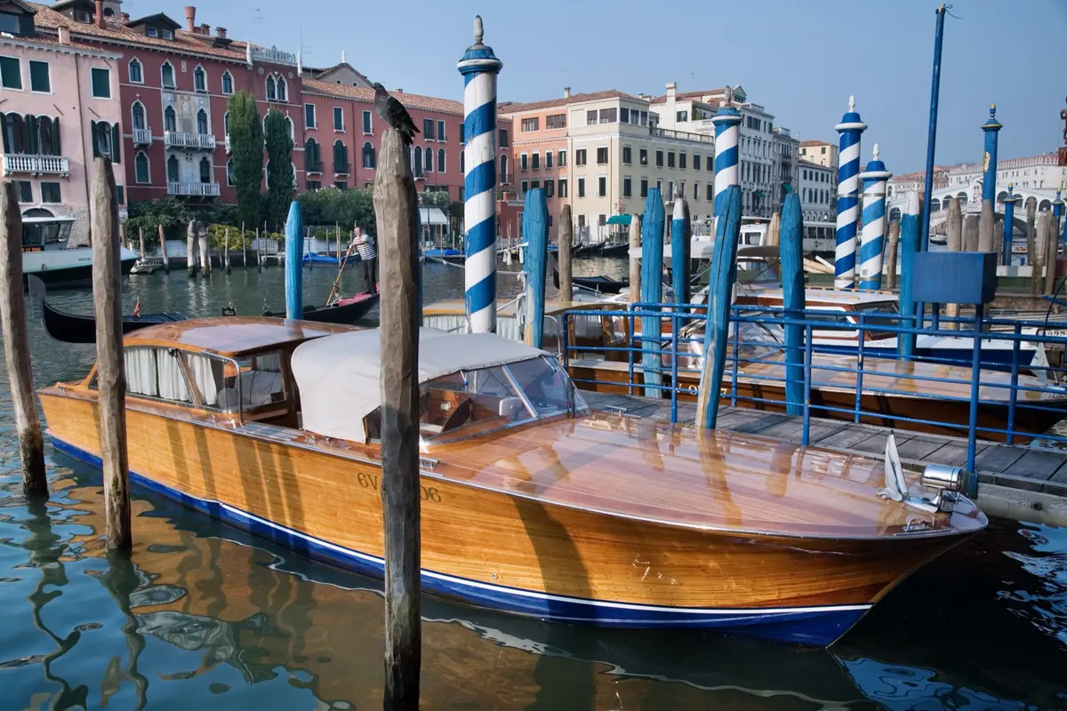 Wooden water taxi moored between striped poles