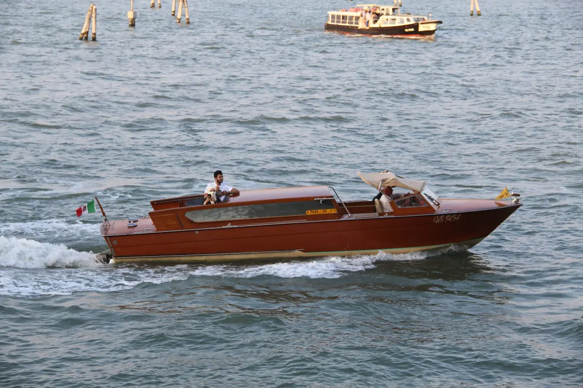 Wooden water taxi carving a wake across the lagoon